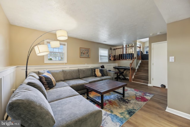 living area featuring wainscoting, a textured ceiling, stairs, and wood finished floors