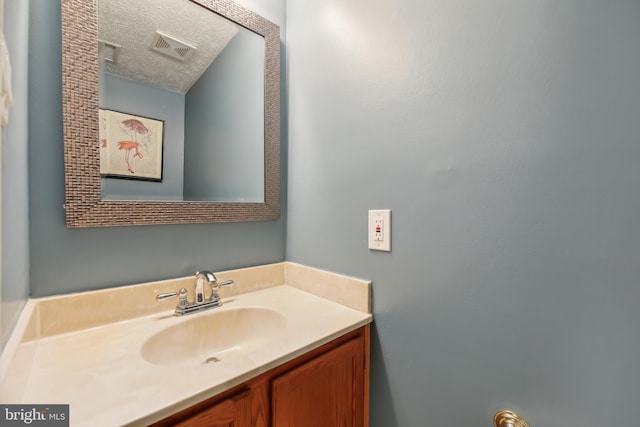 bathroom with visible vents, a textured ceiling, and vanity