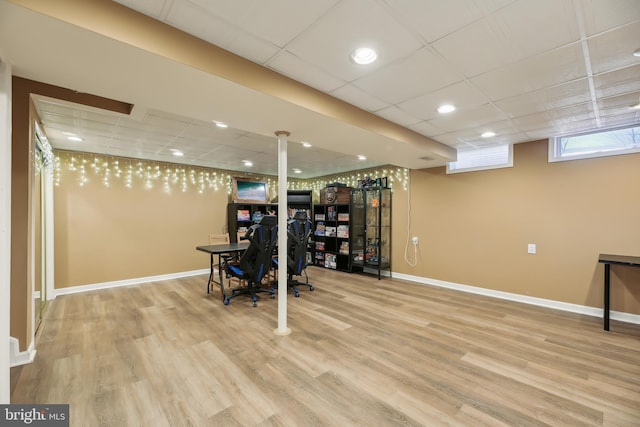 workout room featuring baseboards, a paneled ceiling, and wood finished floors