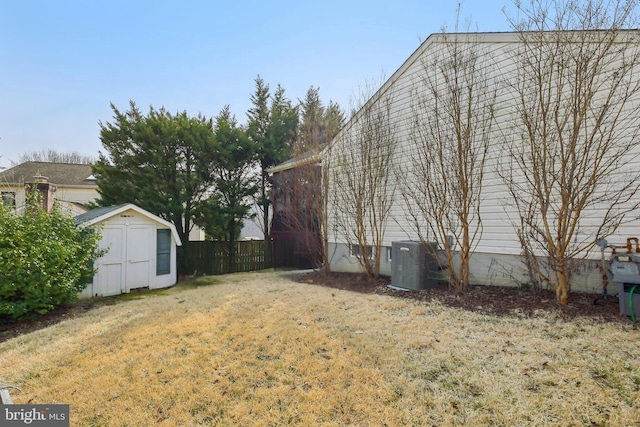 view of yard with central AC, a storage shed, an outdoor structure, and fence