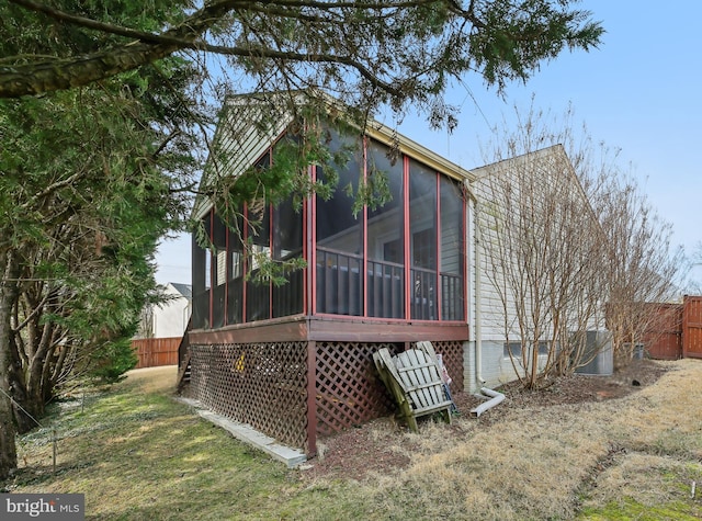 rear view of property featuring fence and a sunroom