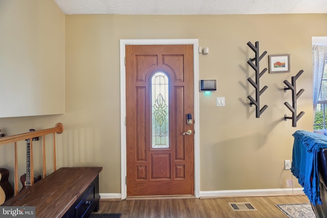 entrance foyer with visible vents, baseboards, and wood finished floors