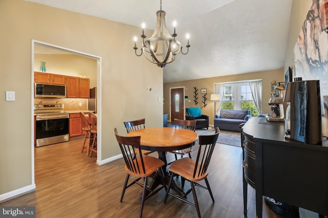 dining space featuring an inviting chandelier, baseboards, and wood finished floors