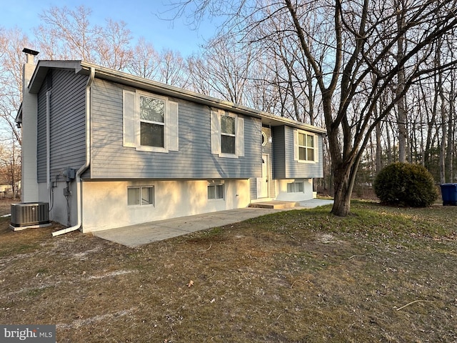 split foyer home with a patio, a chimney, and cooling unit