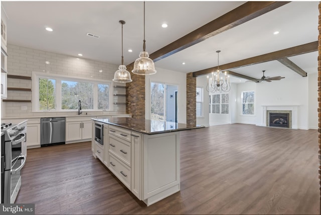 kitchen with stainless steel appliances, a fireplace, white cabinets, open shelves, and tasteful backsplash