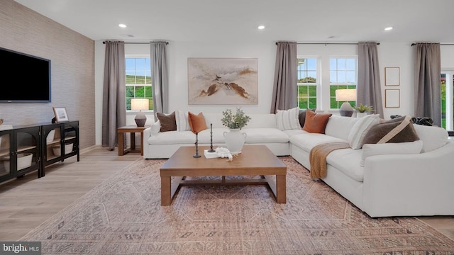 living area with wallpapered walls, light wood-style flooring, an accent wall, and recessed lighting