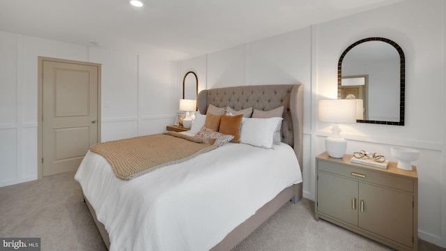 bedroom with light colored carpet and a decorative wall