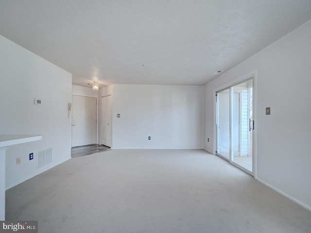 unfurnished living room with carpet, visible vents, and a textured ceiling