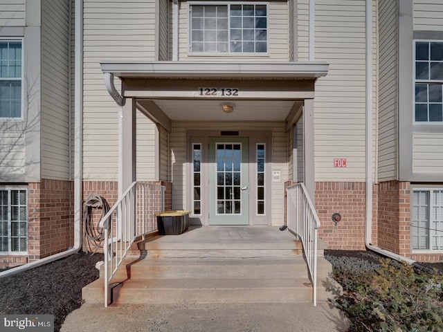 entrance to property with a porch and brick siding