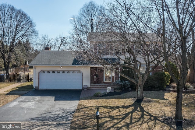 view of front of property featuring brick siding, a chimney, an attached garage, fence, and driveway