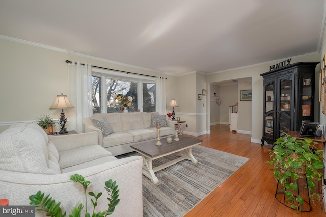 living room featuring stairway, light wood-style flooring, ornamental molding, and baseboards