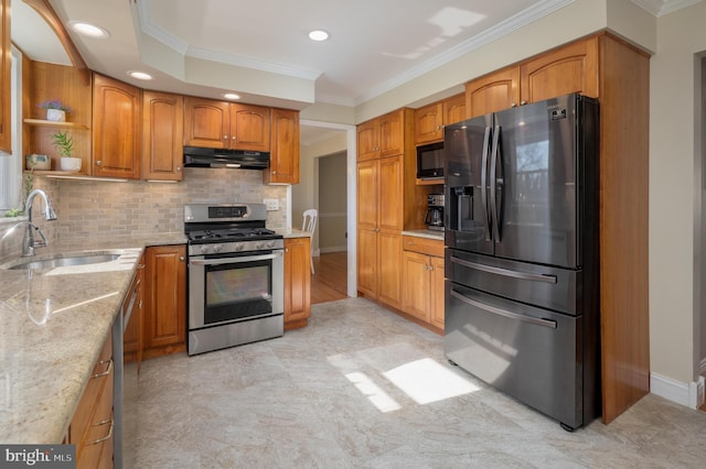 kitchen with ornamental molding, light stone countertops, stainless steel appliances, under cabinet range hood, and a sink