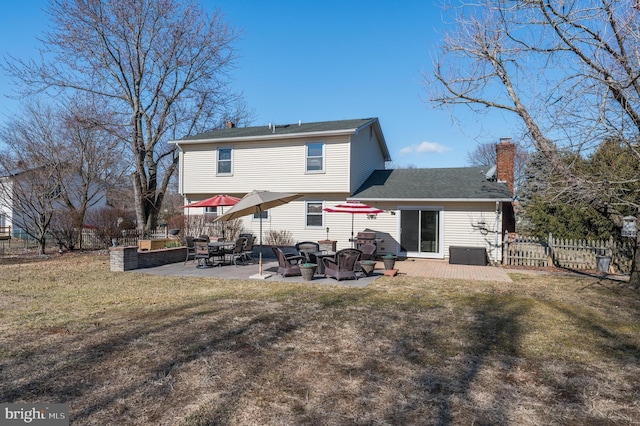 rear view of house with a patio area, fence, a chimney, and a lawn