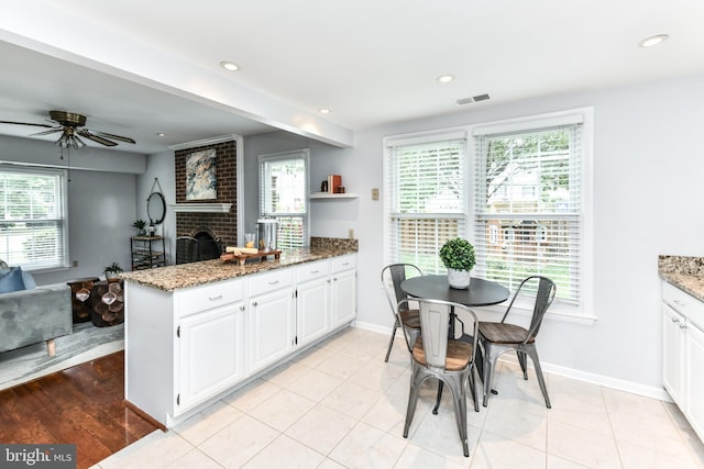 kitchen with a peninsula, light stone countertops, plenty of natural light, and white cabinets