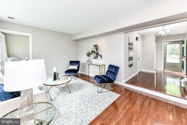 sitting room featuring an inviting chandelier, baseboards, visible vents, and wood finished floors