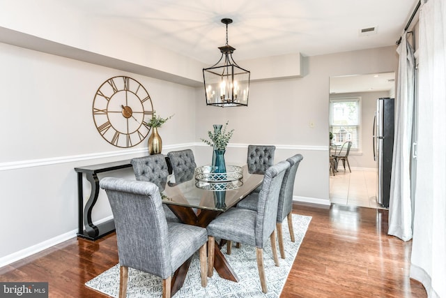 dining area featuring a notable chandelier, wood finished floors, visible vents, and baseboards