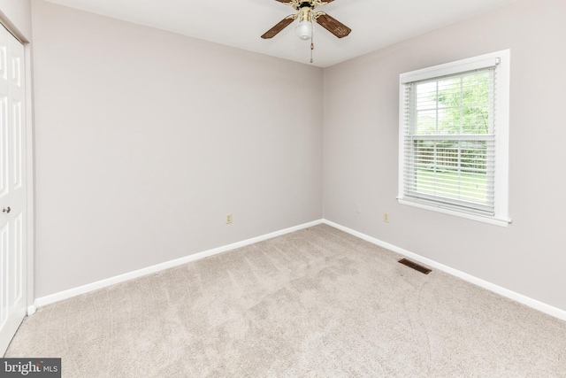 carpeted empty room with a ceiling fan, visible vents, and baseboards