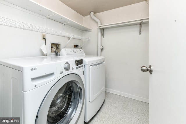 clothes washing area with laundry area, washing machine and clothes dryer, and baseboards