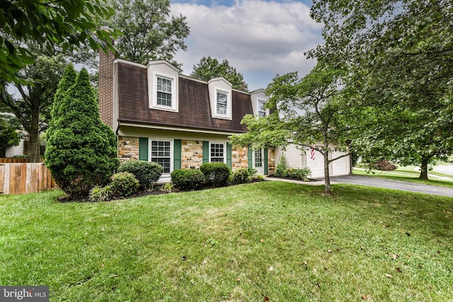 dutch colonial featuring fence, stone siding, driveway, a front lawn, and a chimney