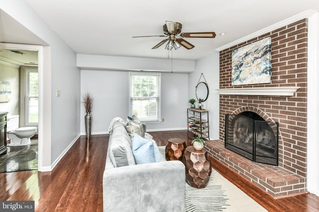 living room featuring a brick fireplace, ceiling fan, baseboards, and wood finished floors