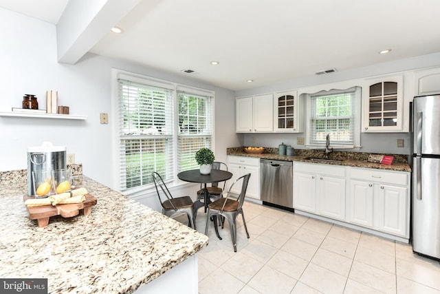 kitchen featuring stone counters, stainless steel appliances, glass insert cabinets, white cabinets, and a sink