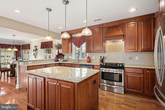 kitchen featuring stainless steel appliances, a peninsula, a sink, visible vents, and custom exhaust hood