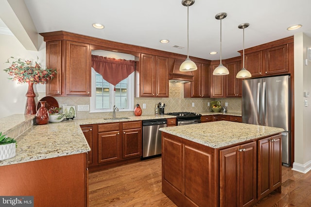 kitchen with light stone counters, custom exhaust hood, light wood-style flooring, appliances with stainless steel finishes, and a sink