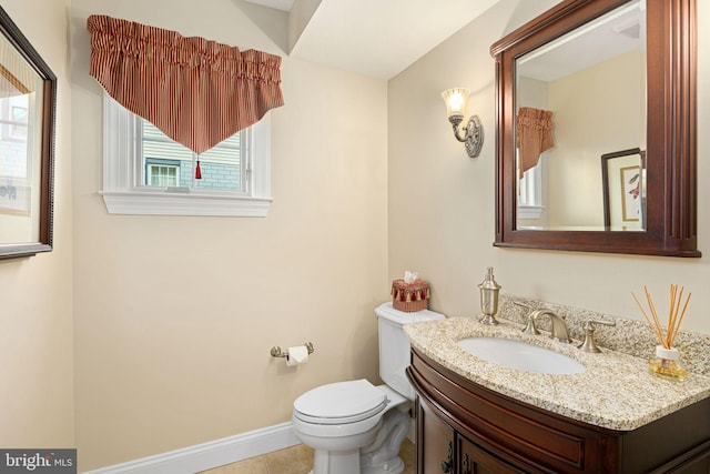 half bathroom with toilet, tile patterned flooring, baseboards, and vanity