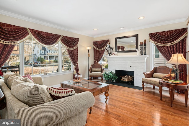 living room with light wood-style flooring, a fireplace, ornamental molding, and recessed lighting