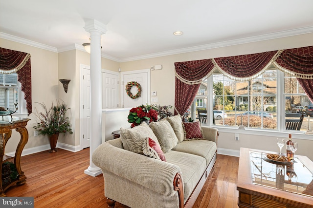 living area featuring ornate columns, crown molding, baseboards, and light wood-style floors