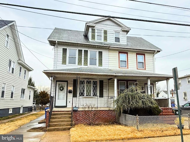 american foursquare style home featuring a porch and fence