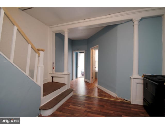 foyer entrance with ornate columns, stairs, baseboards, and dark wood-style flooring