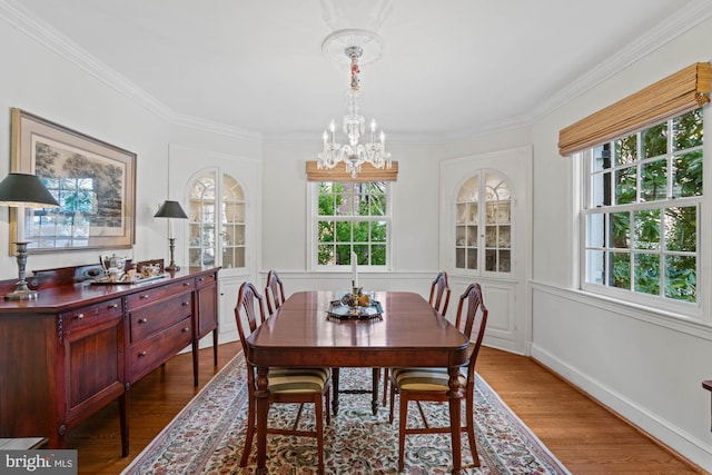 dining room with a chandelier, ornamental molding, and wood finished floors