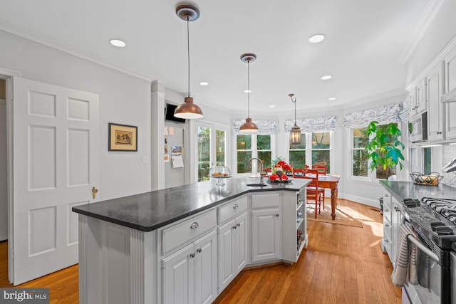 kitchen featuring light wood-type flooring, white cabinets, stainless steel microwave, and dark countertops