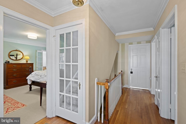 hallway featuring hardwood / wood-style flooring, ornamental molding, and an upstairs landing