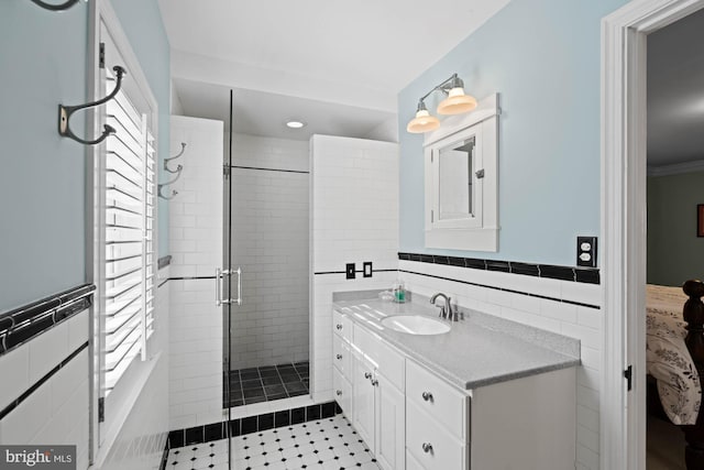 full bath with a stall shower, wainscoting, tile walls, and vanity