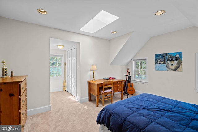 bedroom featuring light carpet, vaulted ceiling with skylight, multiple windows, and baseboards