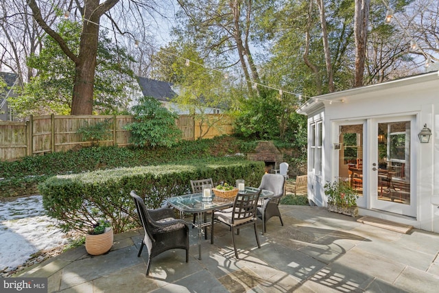 view of patio / terrace with fence, exterior fireplace, and outdoor dining area