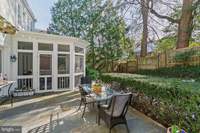 view of patio / terrace featuring a sunroom, fence, and outdoor dining area