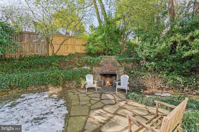 view of patio with an outdoor stone fireplace and fence