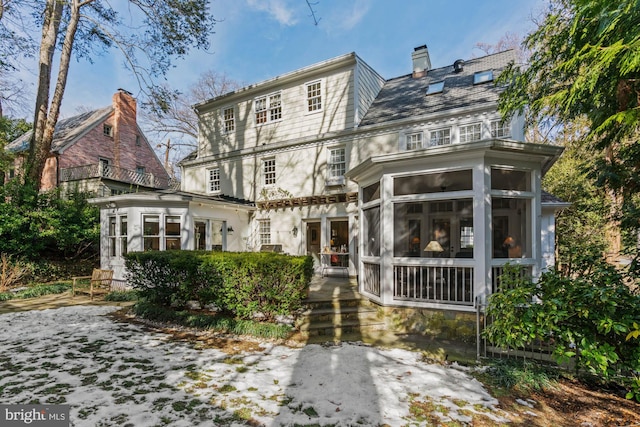 view of front facade featuring a high end roof, a sunroom, and a chimney