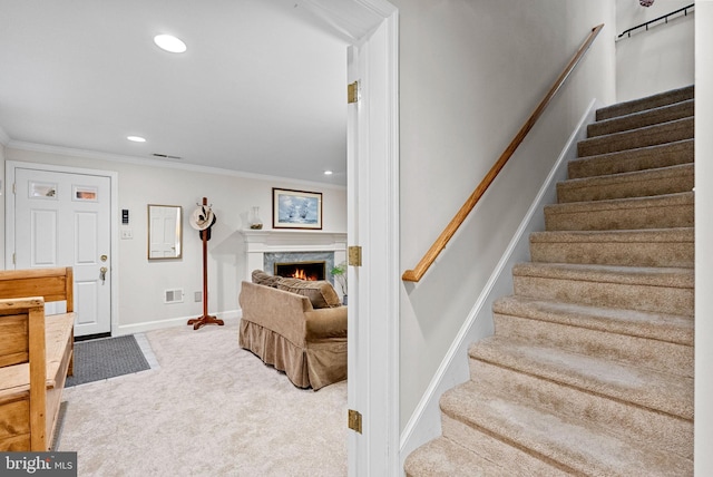 stairs with carpet floors, ornamental molding, a fireplace, and recessed lighting