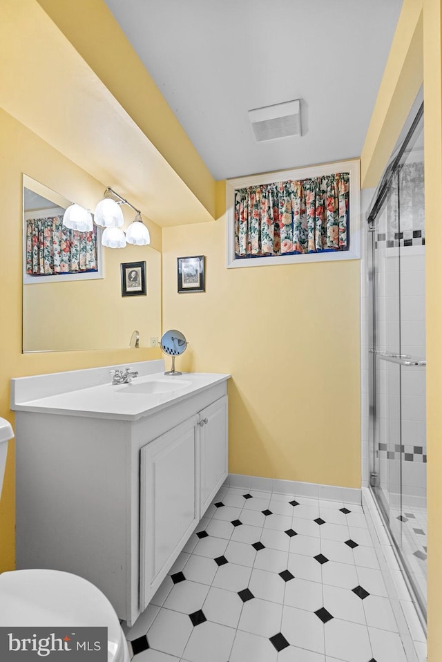 full bathroom featuring a stall shower, baseboards, vanity, and toilet