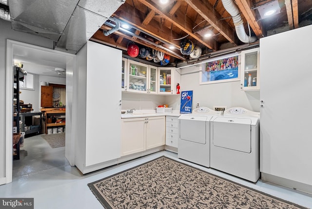 clothes washing area featuring cabinet space, a sink, and separate washer and dryer