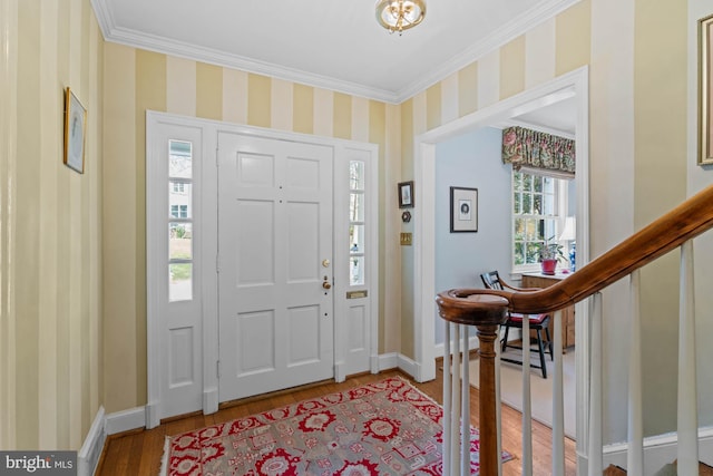 foyer entrance with wallpapered walls, baseboards, ornamental molding, wood finished floors, and stairs