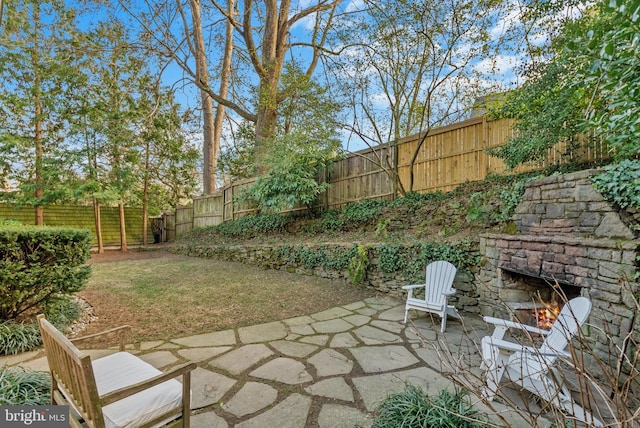 view of patio / terrace with an outdoor stone fireplace and a fenced backyard