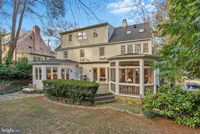 rear view of house featuring a sunroom, a chimney, and a lawn