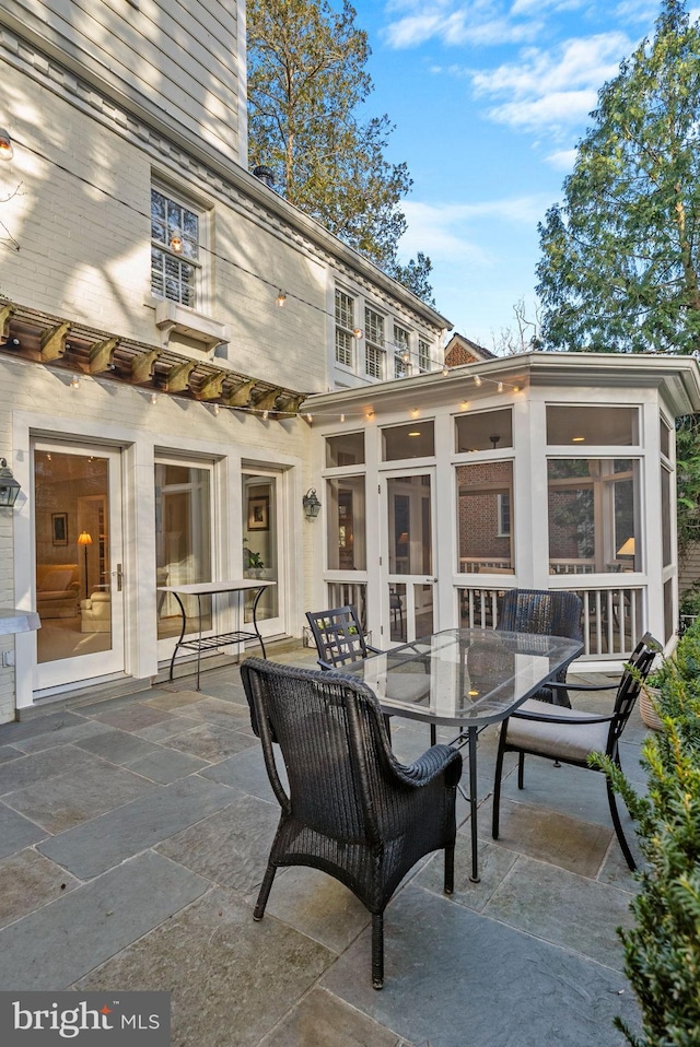 view of patio featuring a sunroom and outdoor dining area