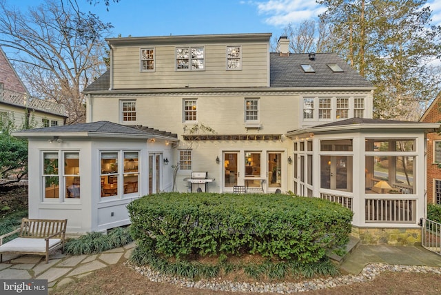 rear view of house with a sunroom and a chimney