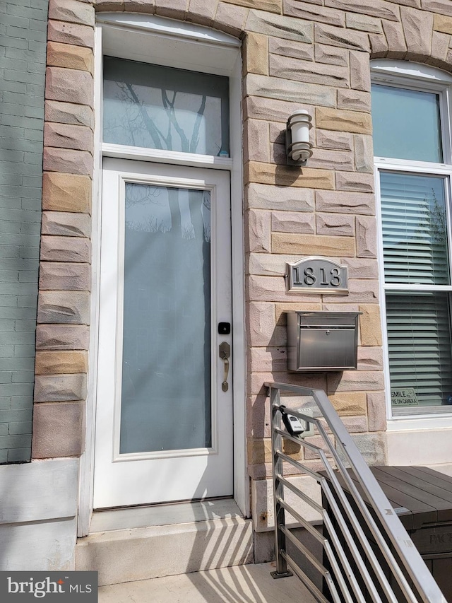 entrance to property featuring stone siding and brick siding